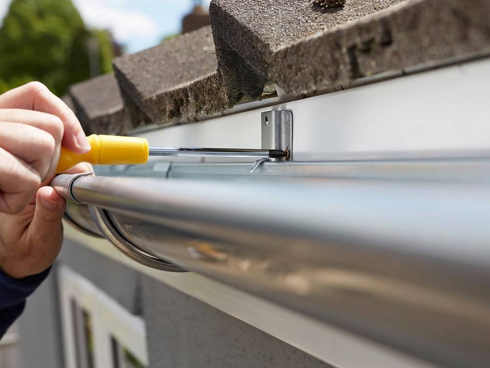 close up of man replacing guttering on exterior of house
